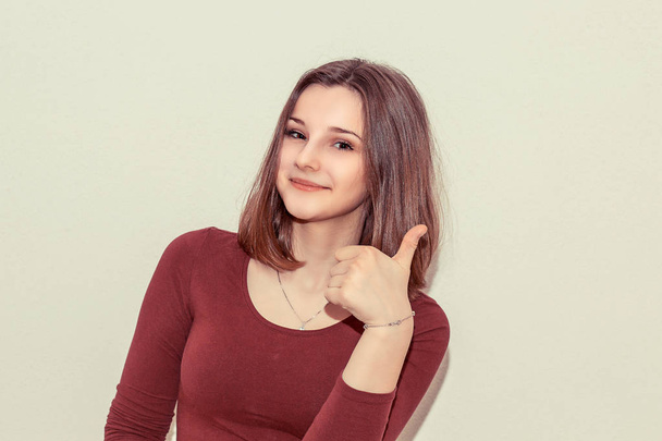 Young teenage woman showing thumb up and smiling at camera on white background - Foto, Imagem