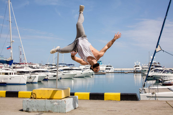 Fitness athlete doing jump squats on makeshift plyo-box on summer sea pier - Photo, Image