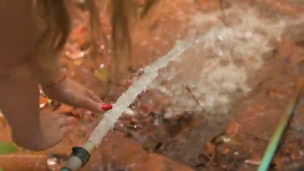 Mujer tirando de la diversión con manguera, salpicaduras de agua en el medio de la selva
 - Metraje, vídeo