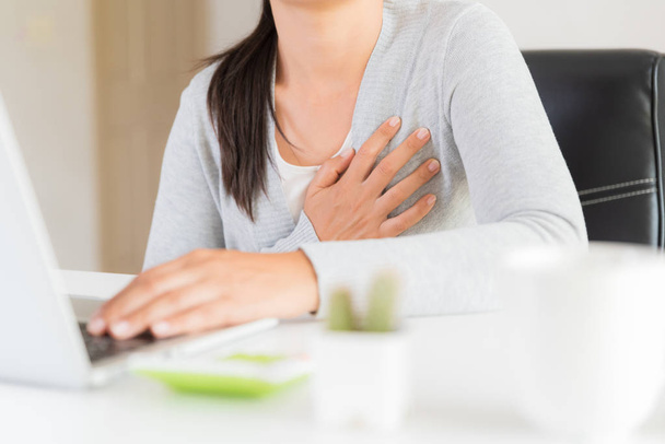 Nahaufnahme Geschäftsfrau mit Herzinfarkt. Frau berührt Brust und hat Brustschmerzen nach stundenlanger Arbeit am Computer. Bürosyndrom, Gesundheitswesen und medizinisches Konzept. - Foto, Bild