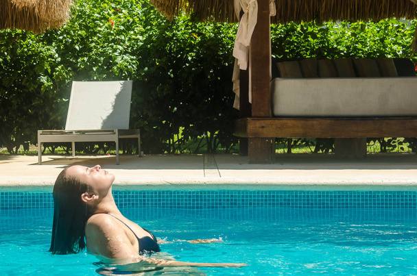 Woman relaxing in an exclusive swimming pool at a caribbean hotel - Photo, Image