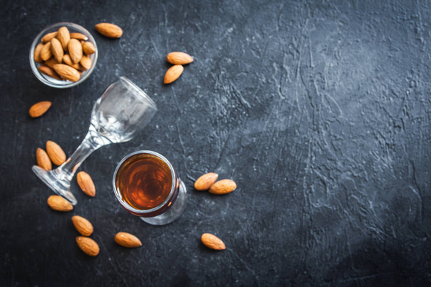 Italian liqueur Amaretto with almonds on black stone background, copy space - Foto, afbeelding