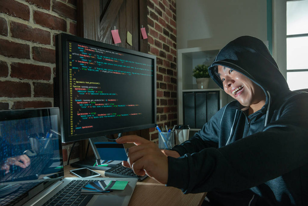 evil hacker holding one bank card and laughing vicously to ready for the next blackmail on his victims. - Photo, image