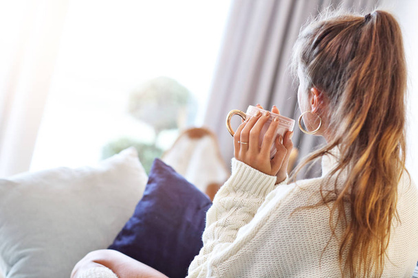 Erwachsene Frau in warmem Pullover ruht sich an einem Herbsttag zu Hause aus - Foto, Bild