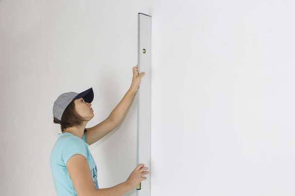 женщина применяет уровень к стене, в новом доме
 - Фото, изображение