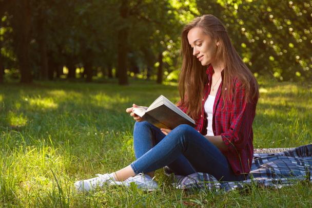 young woman reading book in park at daytime - Foto, Imagen