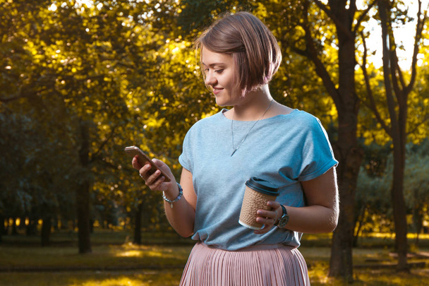 smiling young woman using smartphone in autumn park  - Φωτογραφία, εικόνα