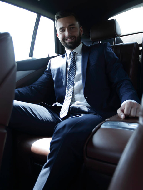 businessman talking on the phone while sitting in the back seat of his car - Foto, afbeelding