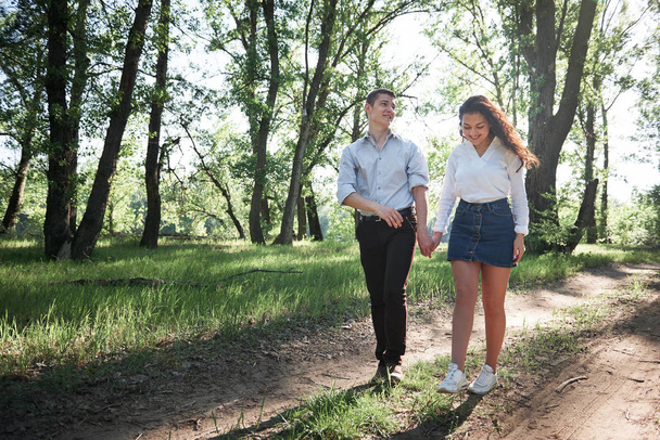junges Paar beim Waldspaziergang, sommerliche Natur, helles Sonnenlicht, Schatten und grüne Blätter, romantische Gefühle - Foto, Bild