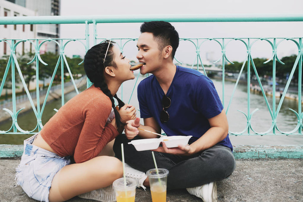 Vietnamese couple biting delicious street food simultaneously - Photo, Image