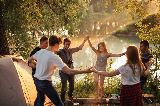 young positive people dancing around the campfire. - Foto, afbeelding