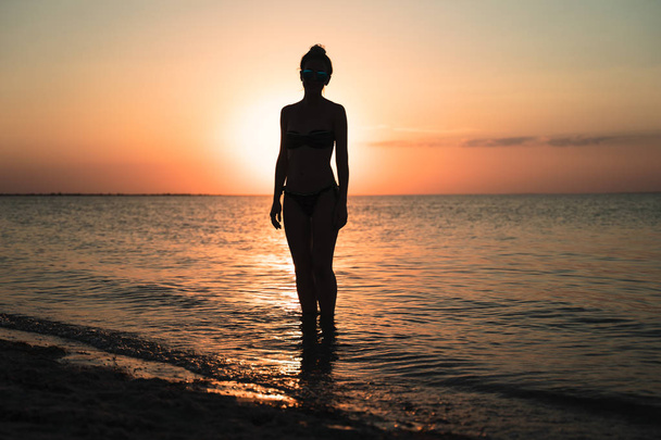 Silueta de la mujer en la playa durante el hermoso atardecer
 - Foto, imagen