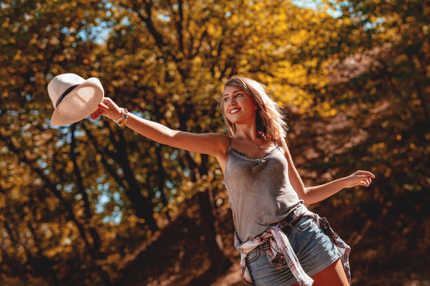 Lächelnde junge Frau genießt im warmen Herbstpark  - Foto, Bild