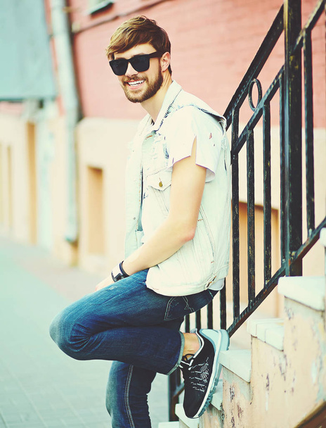 Funny smiling hipster handsome man guy in stylish summer clothes in the street in sunglasses - Fotoğraf, Görsel