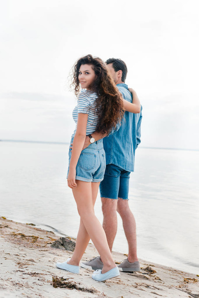 幸せなカップルを抱き締めると、海の近くのビーチの上を歩く  - 写真・画像