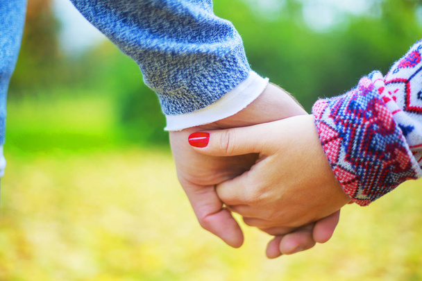 руки счастливой молодой пары, гуляющей и веселящейся в осеннем парке
 - Фото, изображение