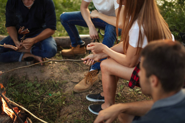 cropped side view photo. teenagers are sitting around the campfire - Valokuva, kuva