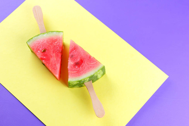 Watermelon pop art. Pieces of watermelon on stick on a yellow purple background. Natural dessert in a minimalist style. Creative story with food for vegan - Fotografie, Obrázek