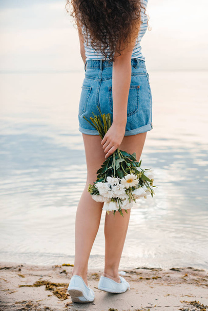 partial view of woman with bouquet standing on sea shore - Fotó, kép