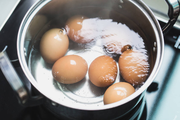 Kochen von Eiern oder gekochtes Ei Kochen in heißem Wasser Schüssel mit hohem Eiweiß fettarme Nahrung - Foto, Bild