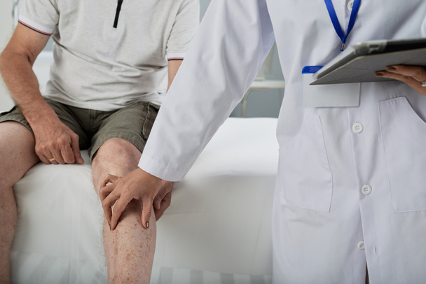 傷害の後の人間の脚を触診医師 - 写真・画像