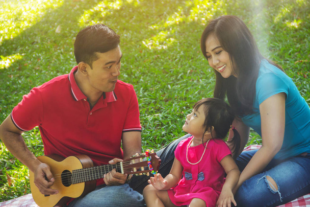 Семейный отдых, играет музыку и веселится вместе на природе
 - Фото, изображение