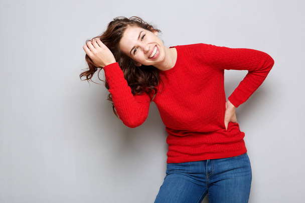 Портрет счастливой молодой женщины, смеющейся с рукой в волосах
 - Фото, изображение