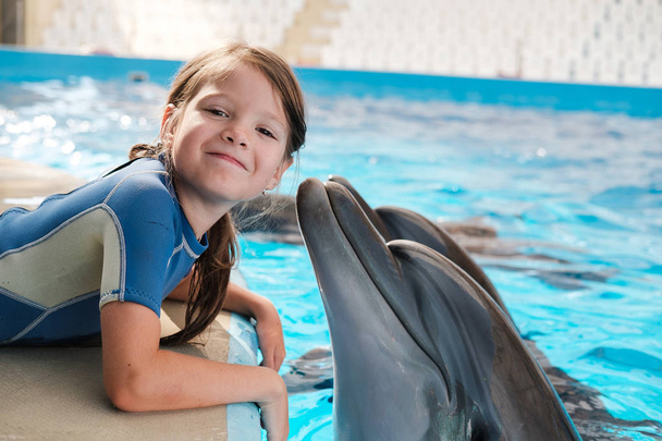 Tyttö ui pullonokkadelfiinien kanssa sinisessä vedessä. Delfiini avusteinen hoito
 - Valokuva, kuva