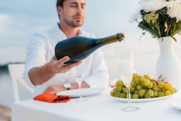 foco seletivo do homem derramando champanhe em vidro na data romântica
 - Foto, Imagem