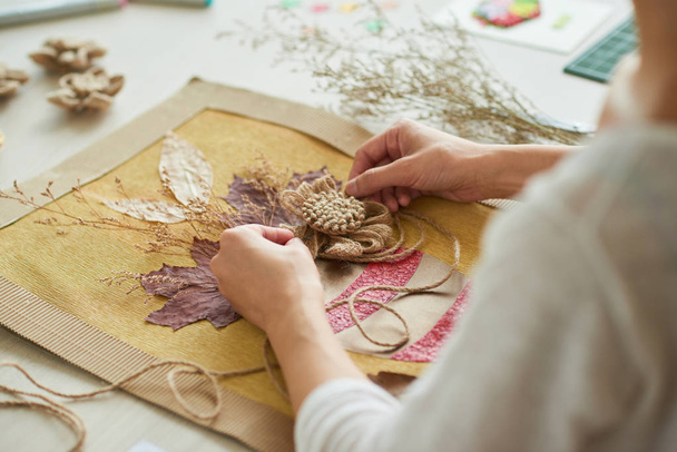 woman decorating textile picture with flowers  - Photo, Image