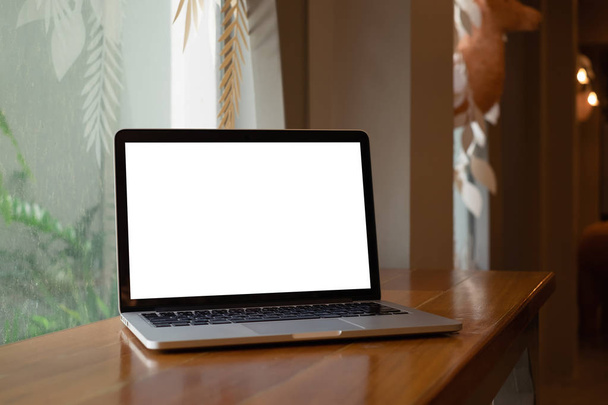 Laptop komputer z pustym ekranem na drewnianym biurku w kawiarni. - Zdjęcie, obraz