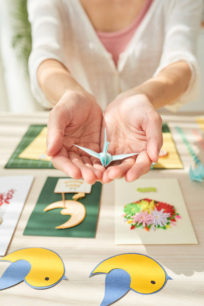 Handen van vrouw bedrijf kleine origami kraan - Foto, afbeelding