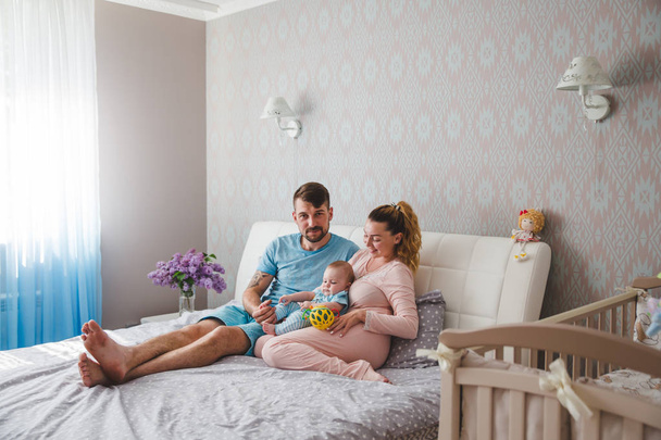Portret van gelukkige jonge ouders met baby thuis - Foto, afbeelding