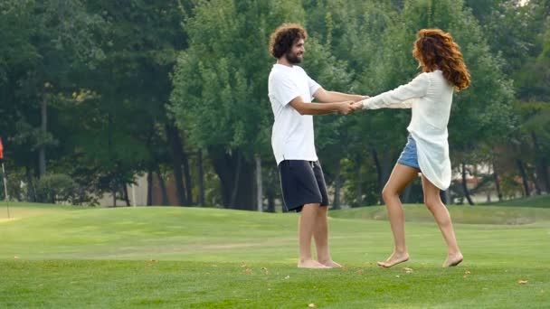 Feliz casal apaixonado desfrutando de bom dia de verão no parque da cidade. De mãos dadas e rodopiar. Movimento lento
. - Filmagem, Vídeo
