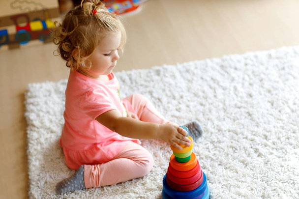 Чарівна мила красива маленька дівчинка грає з освітньою барвистою дерев'яною іграшковою пірамідою дощовика
 - Фото, зображення