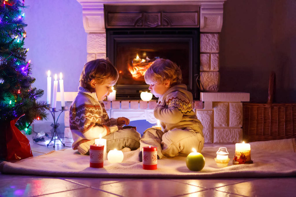 Jolis tout-petits garçons, jumeaux blonds jouant ensemble et lookinig sur le feu dans la cheminée. Famille célébrant Noël vacances - Photo, image