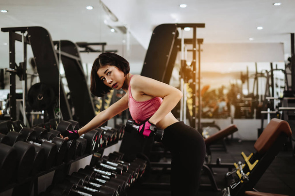 Atrakcyjna kobieta fit treningu z hantle w siłowni fitness. Portret sport i zdrowy koncepcja. - Zdjęcie, obraz