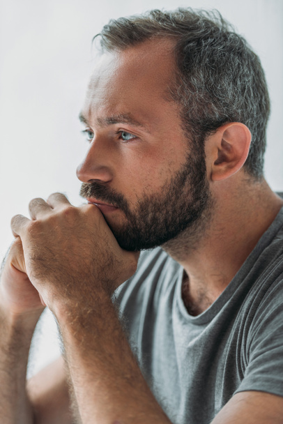 close-up view of sad handsome bearded man holding hands on chin and looking away - Foto, Imagen