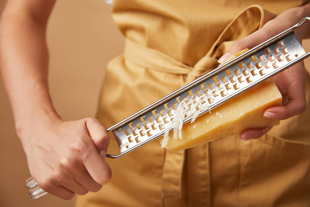 cropped shot of woman in yellop apron grating cheese - Φωτογραφία, εικόνα