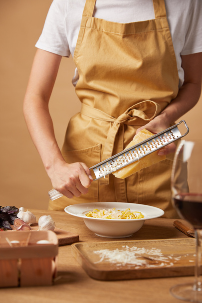 cropped shot of woman grating cheese while cooking pasta - Photo, Image