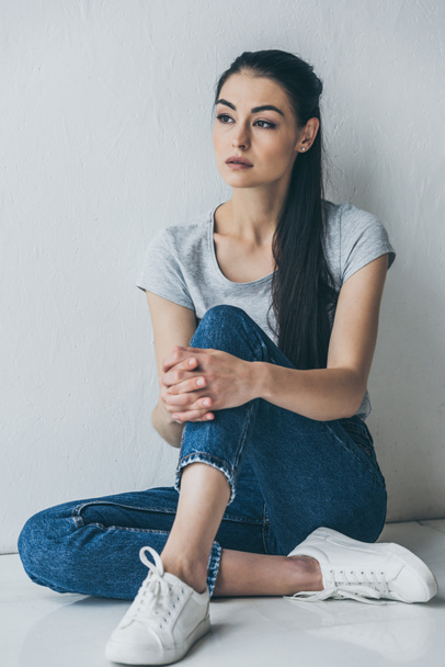 full length view of depressive attractive brunette girl sitting and looking away - Foto, afbeelding