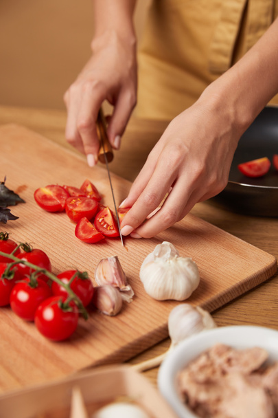 cropped shot of woman cutting cherry tomatoes for pasta - Fotó, kép