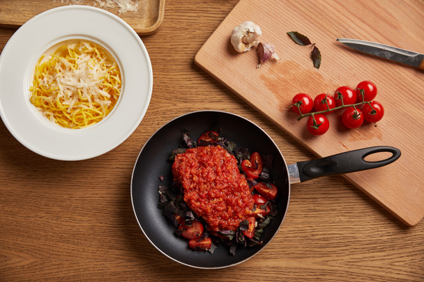 vista superior del plato de espaguetis y salsa de tomate en sartén sobre mesa de madera
 - Foto, Imagen