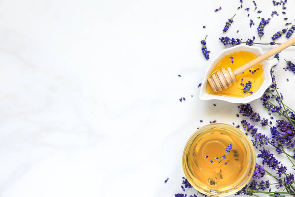 cup of lavender tea with honey and fresh flowers over white marble table. herbal drink. top view with copy space - Photo, image
