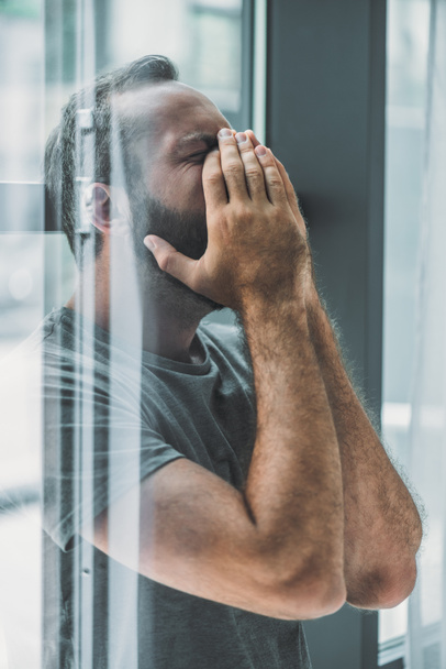 boční pohled na depresi frustrovaný vousatý muž s pláčem ruce na obličej - Fotografie, Obrázek