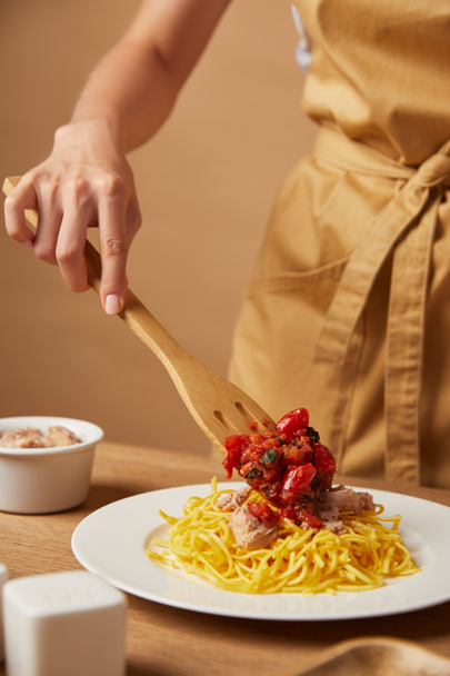 cropped shot of woman putting sauce onto pasta with wooden spatula - Valokuva, kuva