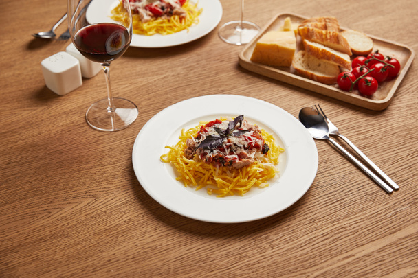 κοντινή λήψη ενός πιάτα μακαρόνια με κόκκινο κρασί σε ποτήρια για ρομαντικό δείπνο - Φωτογραφία, εικόνα