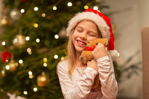 smiling girl in santa hat with christmas gift - Fotoğraf, Görsel