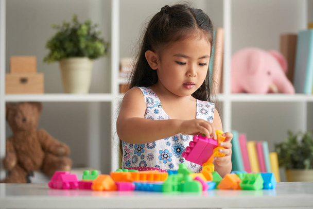 Маленька дівчинка грає з яскравими пластиковими блоками
 - Фото, зображення
