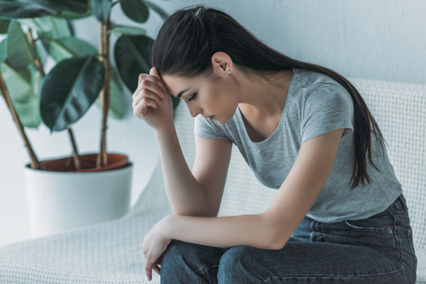 frustrado jovem mulher em depressão sentado no sofá e olhando para baixo
 - Foto, Imagem